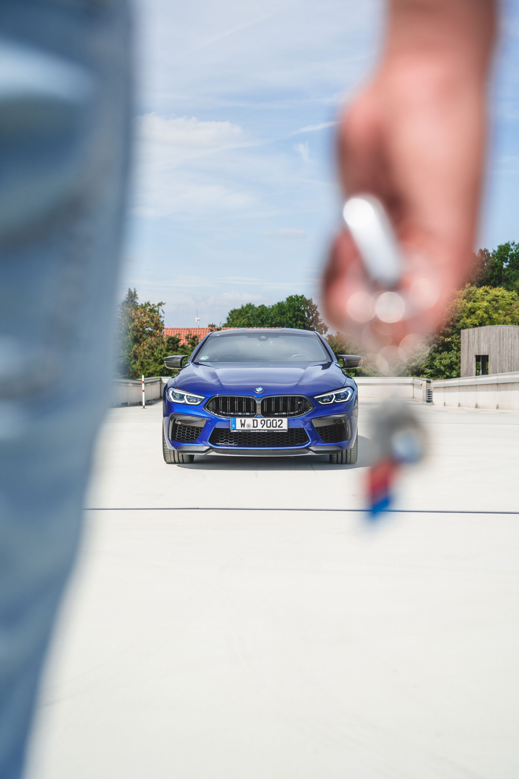 Mann hält Schlüssel in der Hand und läuft zu seinem blauen BMW